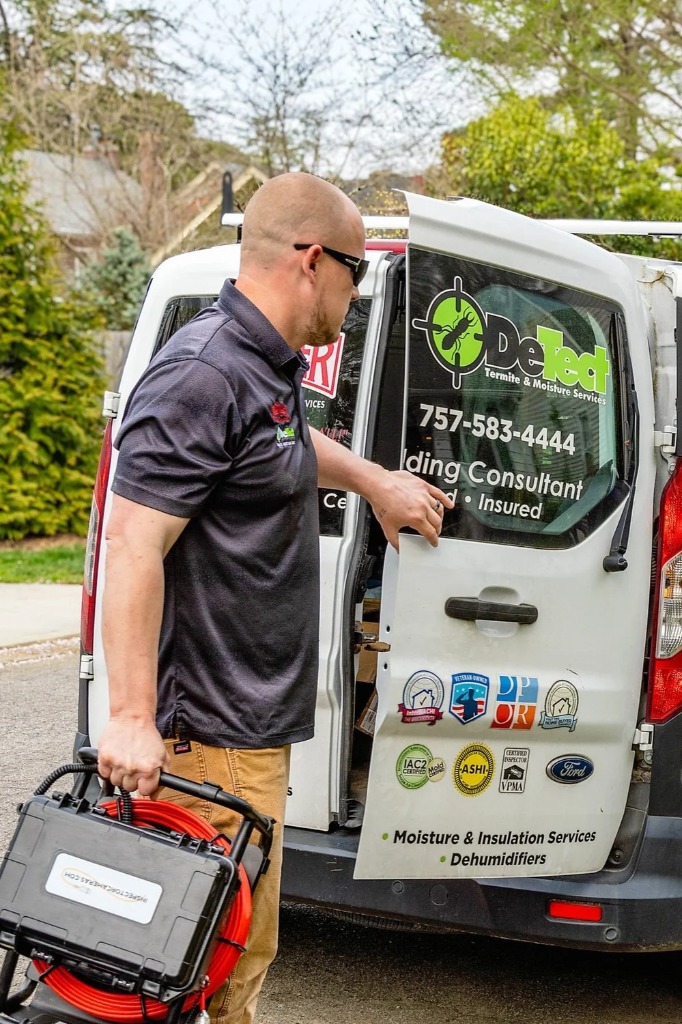 Detect Termite technician taking equipment from the back of a branded service van at a Hampton Roads home